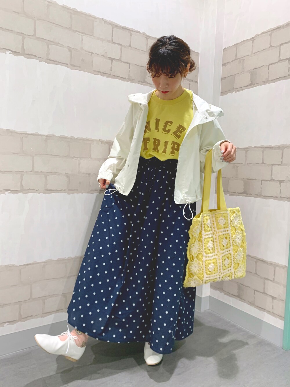 イエロー系のトートバッグ、イエロー系のTシャツ/カットソー、ホワイト系のマウンテンパーカーを着用したレディースの春コーディネートの1枚目の写真