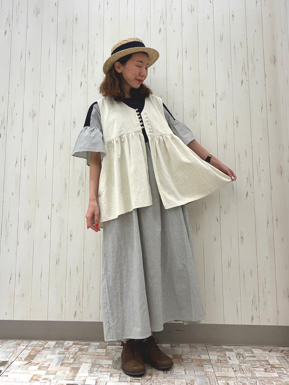 ホワイト系のベスト、ベージュ系のドレスシューズ、ブラック系のワンピースを着用したレディースの春コーディネートの1枚目の写真