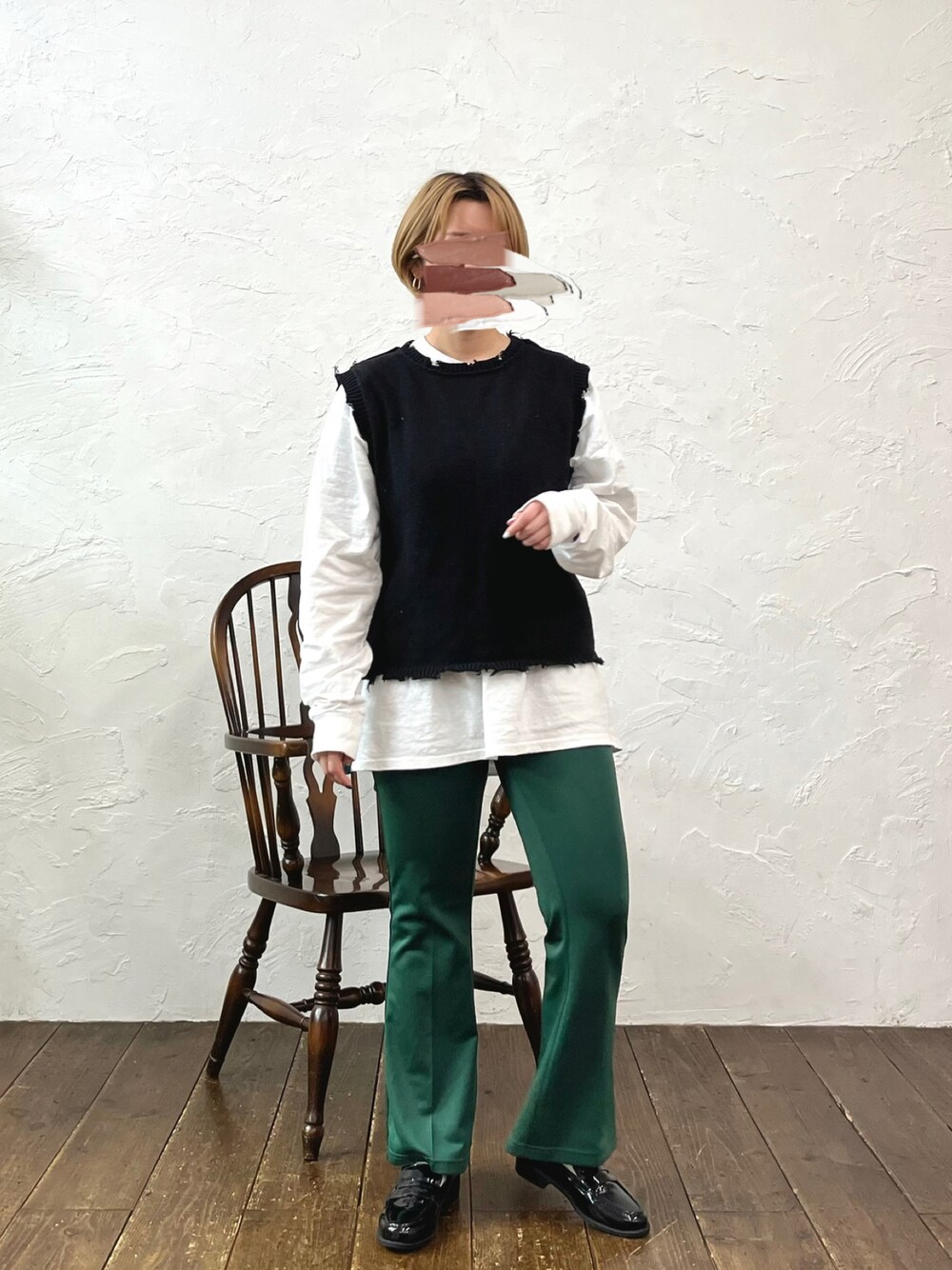 グリーン系のスラックス、ブラック系のニット/セーター、ホワイト系のTシャツ/カットソーを着用したレディースの冬コーディネートの1枚目の写真