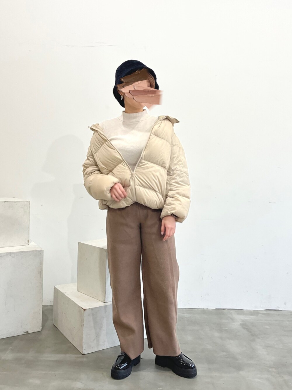 ブラウン系のその他パンツ、ベージュ系のダウンジャケット/コート、ホワイト系のニット/セーターを着用したレディースの冬コーディネートの1枚目の写真