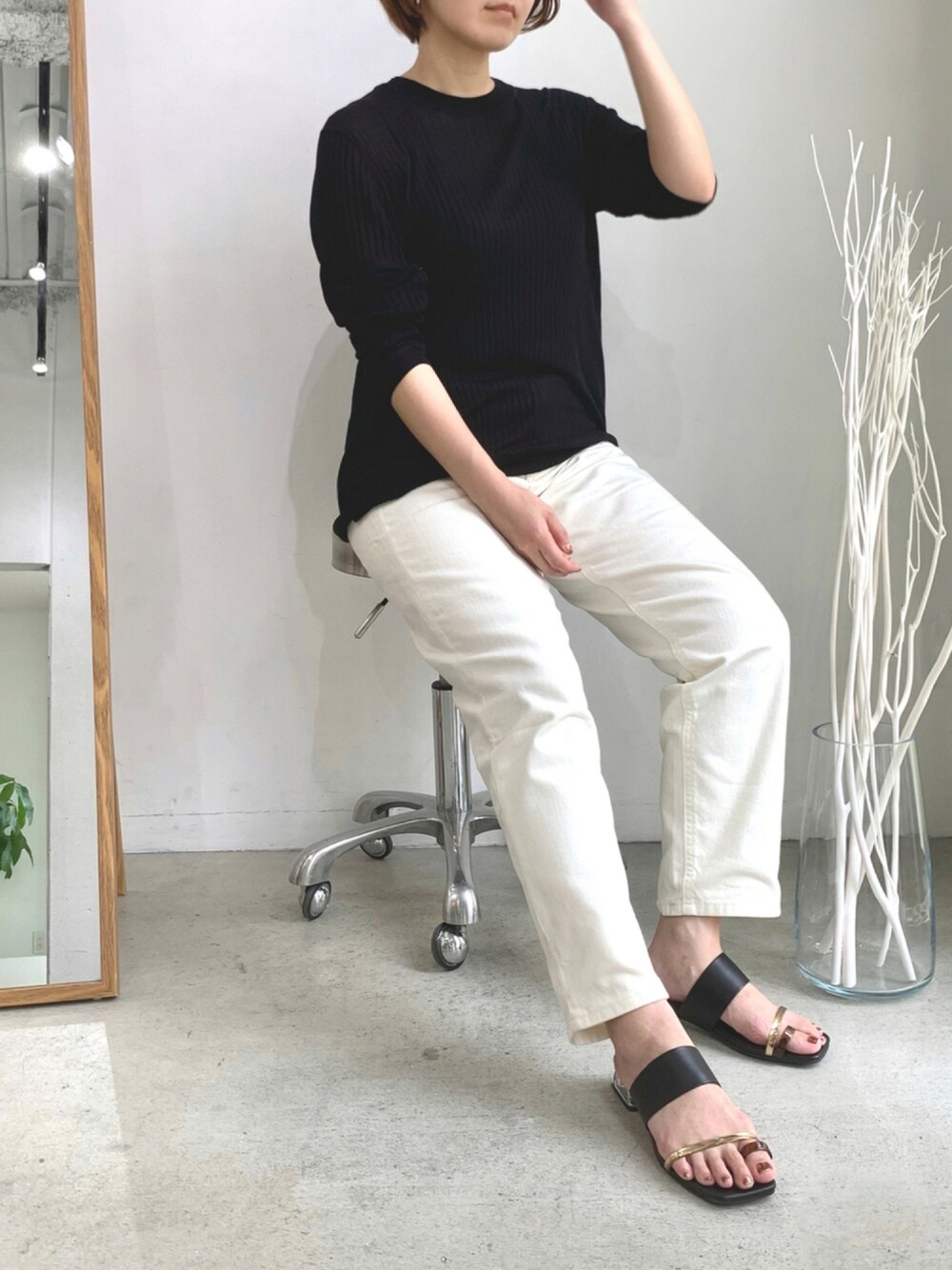 ブラック系のサンダル、ブラック系のニット/セーター、ホワイト系のデニムパンツを着用したレディースの夏コーディネートの1枚目の写真