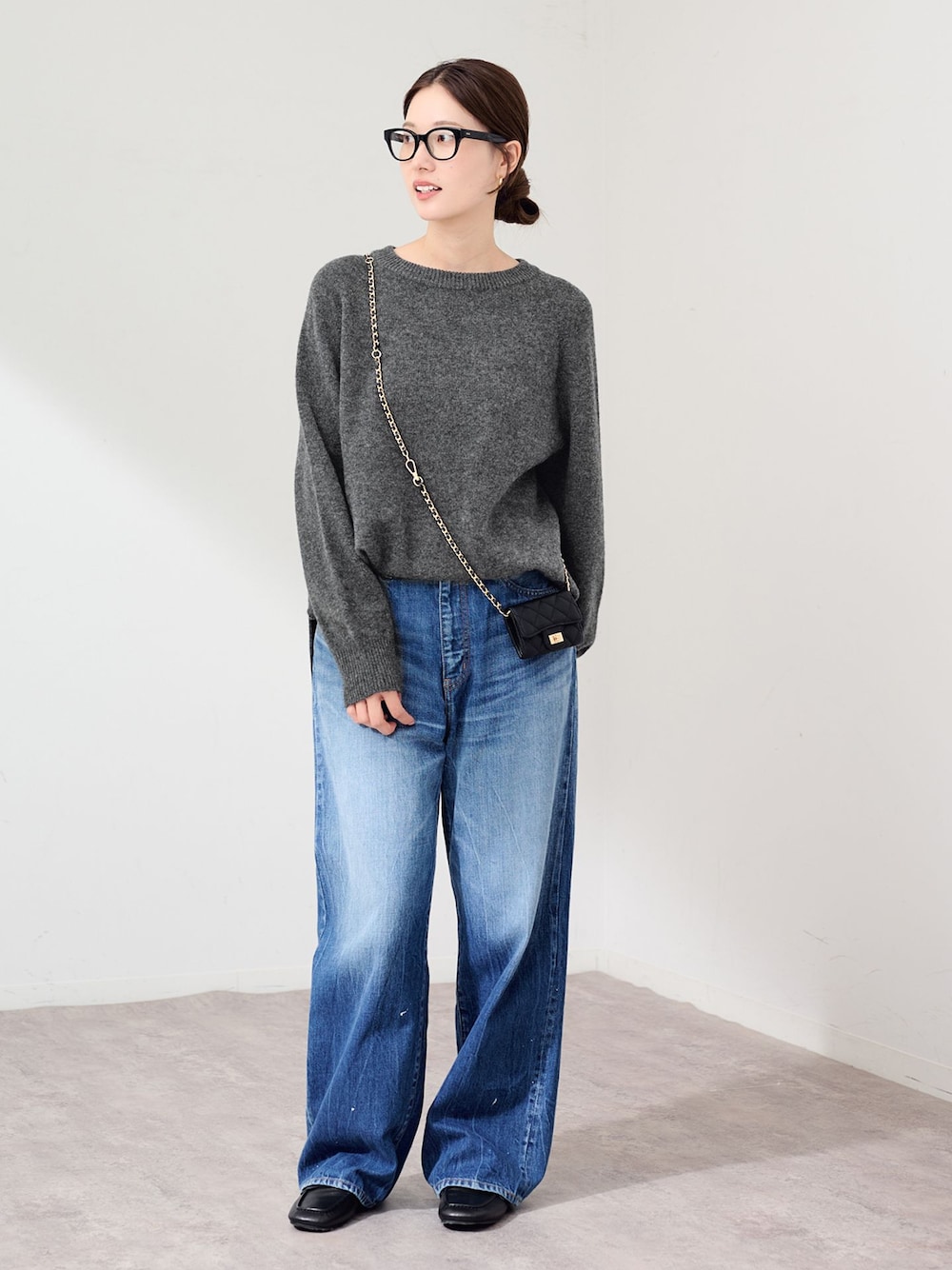 ブルー系のデニムパンツ、グレー系のニット/セーター、ブラック系のスリッポンを着用したレディースの秋コーディネートの1枚目の写真