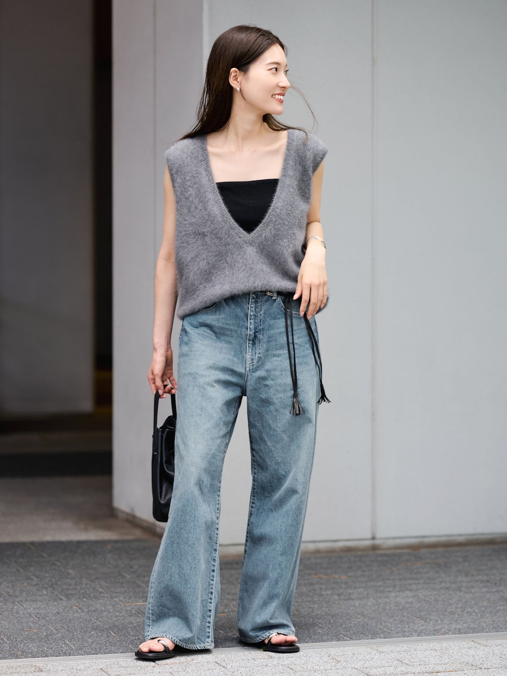 ブルー系のデニムパンツ、グレー系のベスト、ブラック系のハンドバッグを着用したレディースの夏コーディネートの1枚目の写真