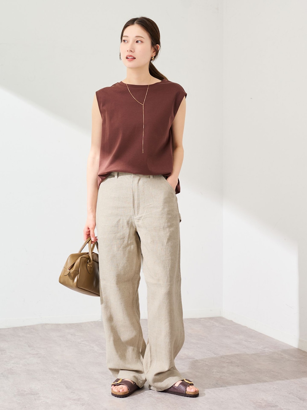 ベージュ系のデニムパンツ、ブラウン系のTシャツ/カットソー、ブラウン系のショルダーバッグを着用したレディースの夏コーディネートの1枚目の写真