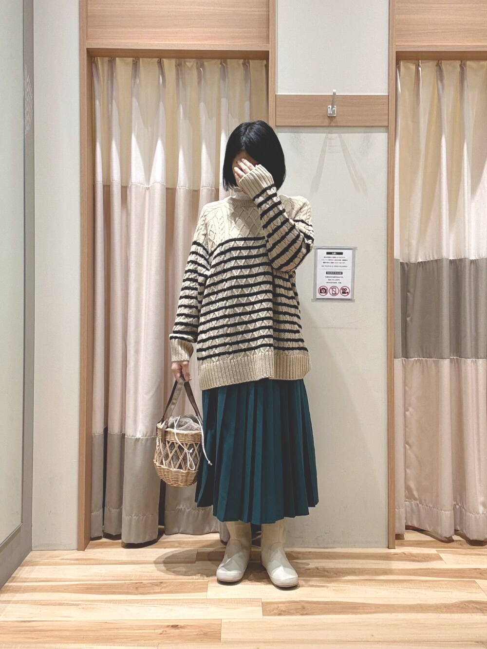 ベージュ系のニット/セーター、ベージュ系のハンドバッグ、グリーン系のスカートを着用したレディースの冬コーディネートの1枚目の写真