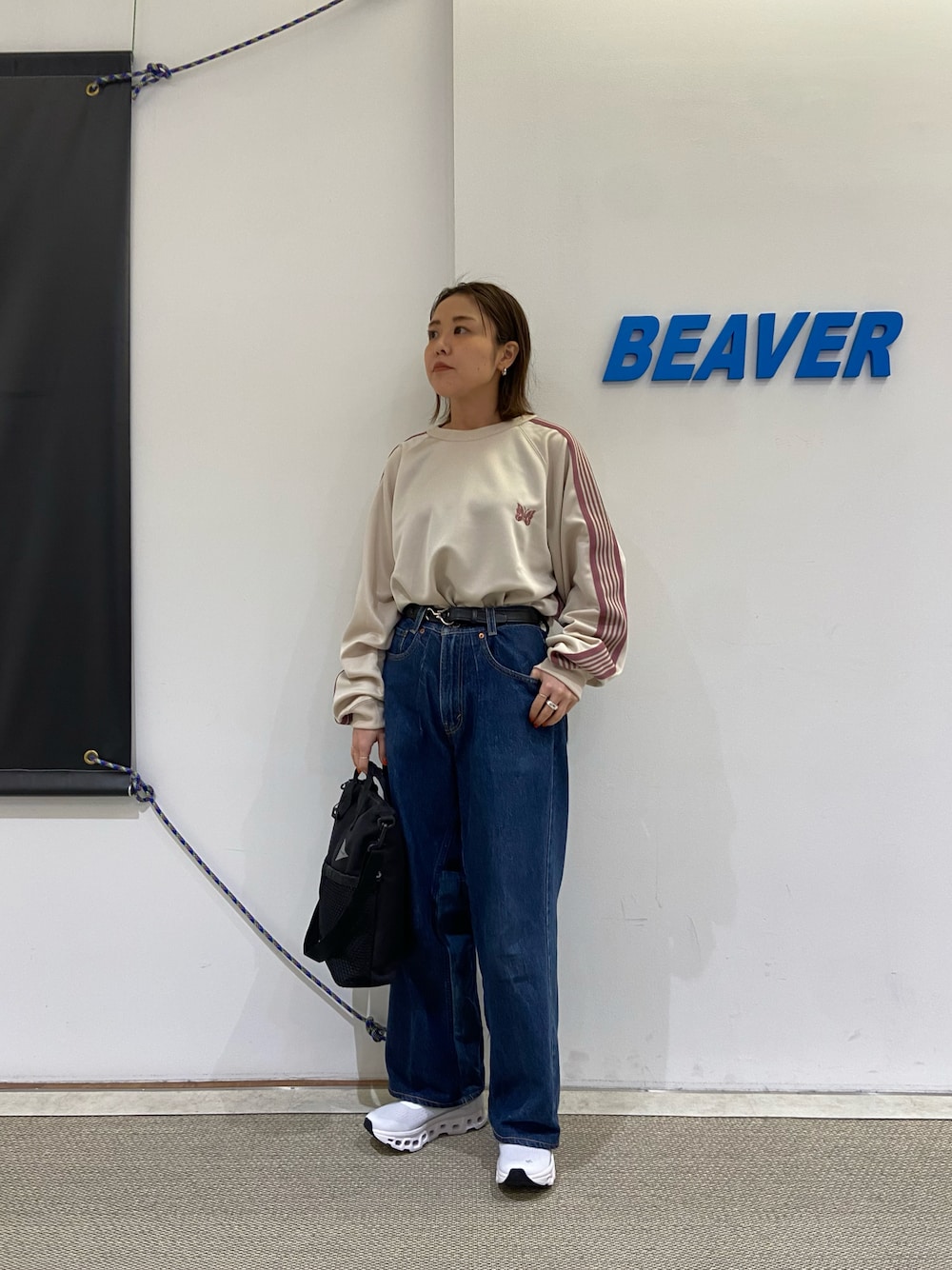 ホワイト系のスニーカー、グレー系のショルダーバッグ、ブラック系のベルトを着用したレディースの冬コーディネートの1枚目の写真