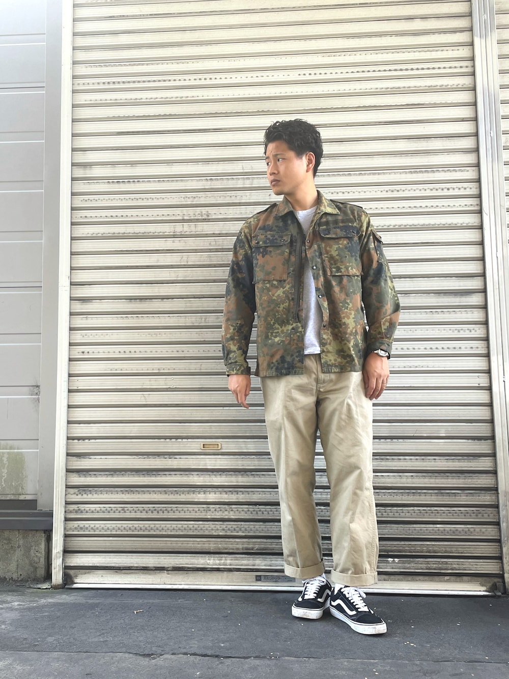 ベージュ系のチノパンツ、グリーン系のミリタリージャケット、グレー系のTシャツ/カットソーを着用したメンズの秋コーディネートの1枚目の写真