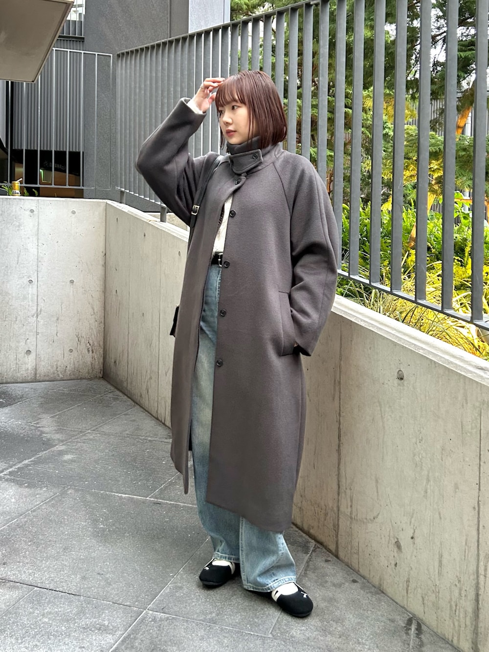 グレー系のステンカラーコート、ホワイト系のニット/セーター、ブルー系のデニムパンツを着用したレディースの秋コーディネートの1枚目の写真