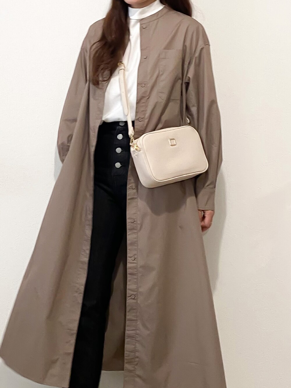 ベージュ系のショルダーバッグ、ブラウン系のシャツワンピース、ホワイト系のTシャツ/カットソーを着用したレディースの秋コーディネートの1枚目の写真