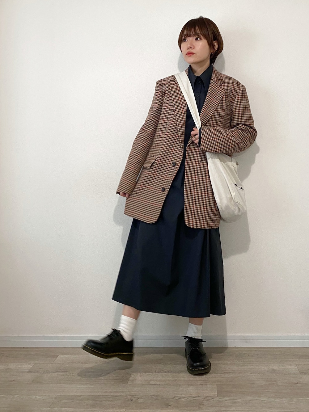 ブラック系のシャツワンピース、ブラウン系のテーラードジャケット、ホワイト系のショルダーバッグを着用したレディースの秋コーディネートの1枚目の写真