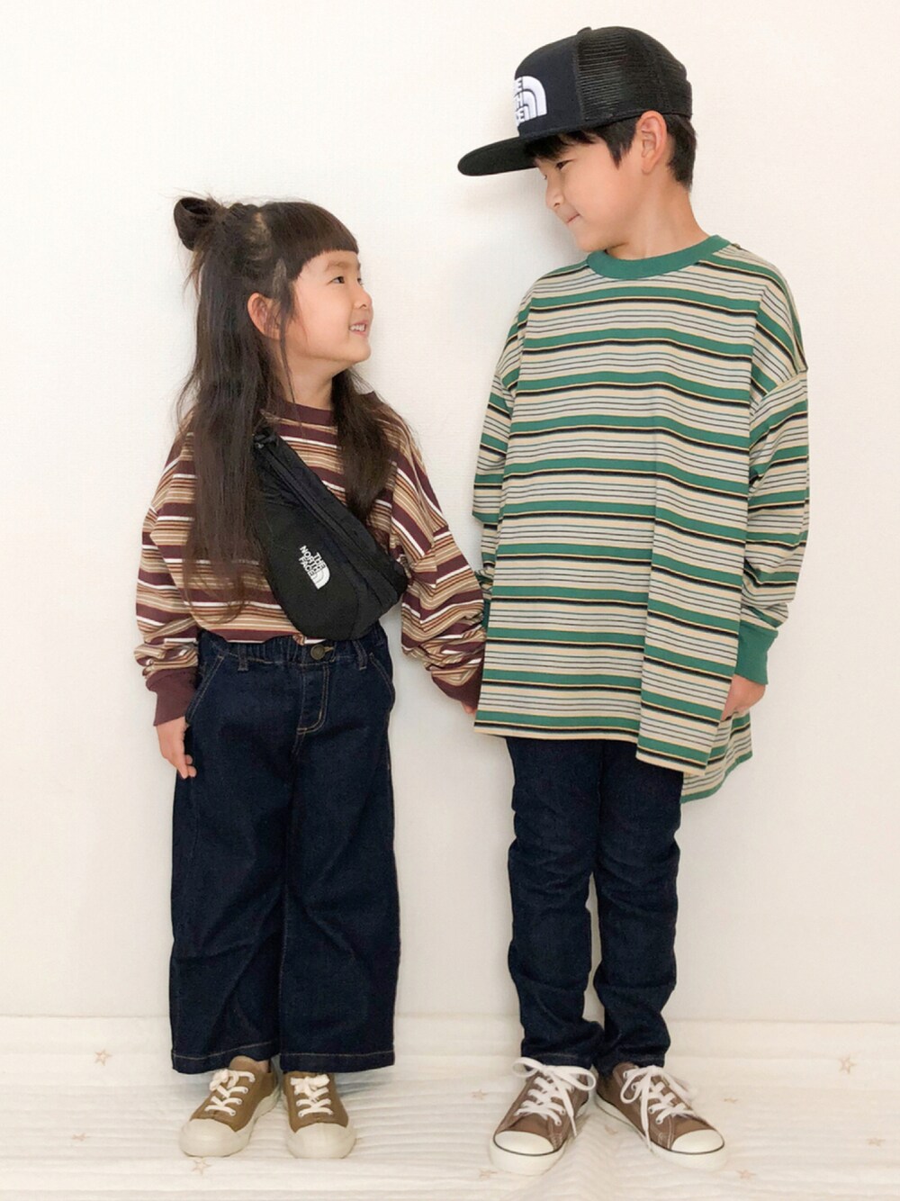 グリーン系のTシャツ/カットソー、ブラウン系のTシャツ/カットソー、ブルー系のデニムパンツを着用したキッズの秋コーディネートの1枚目の写真