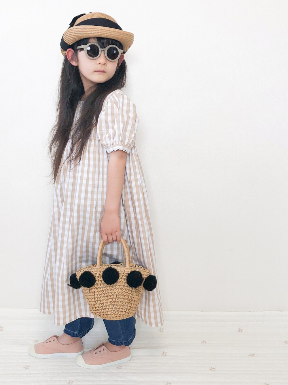 ベージュ系のシャツワンピース、ベージュ系のデニムパンツを着用したキッズの夏コーディネートの1枚目の写真