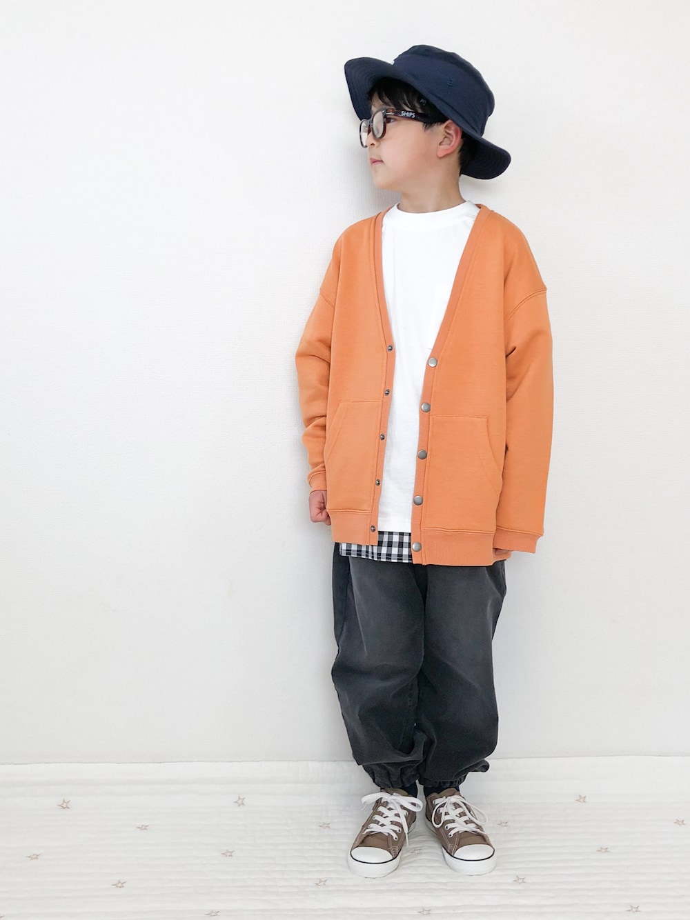 グレー系のデニムパンツ、オレンジ系のカーディガン/ボレロ、ホワイト系のTシャツ/カットソーを着用したキッズの春コーディネートの1枚目の写真