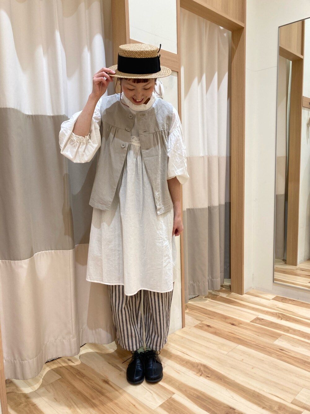 ホワイト系のチュニック、ベージュ系のベスト、グレー系のその他パンツを着用したレディースの春コーディネートの1枚目の写真