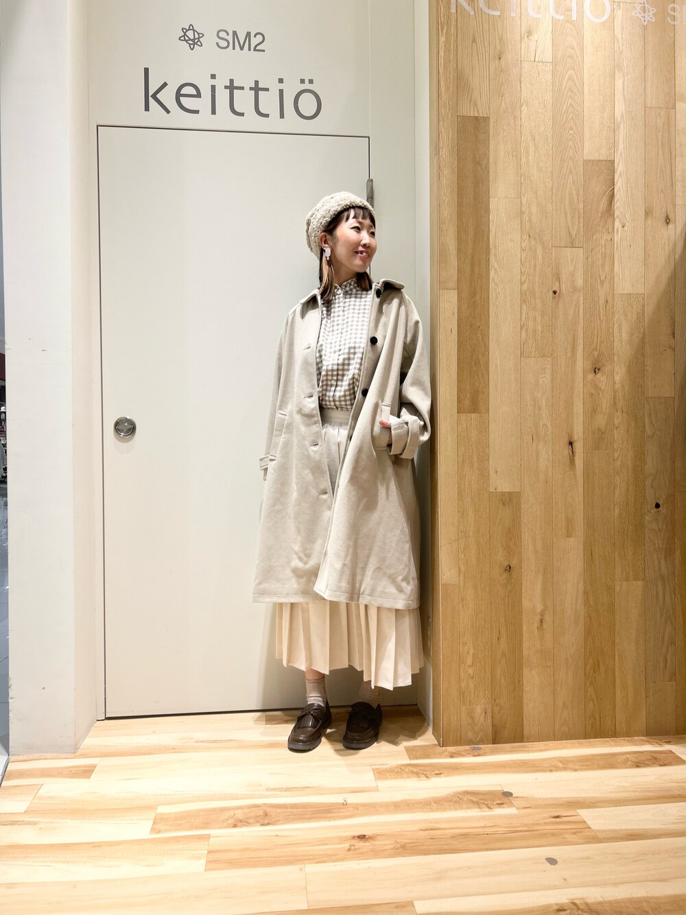 ベージュ系のシャツ/ブラウス、ベージュ系のステンカラーコート、ホワイト系のスカートを着用したレディースの冬コーディネートの1枚目の写真