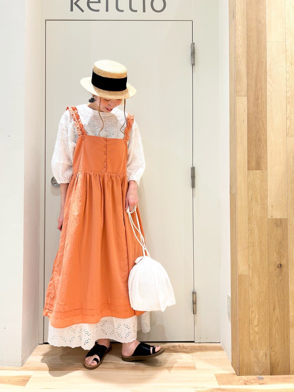 オレンジ系のワンピース/ドレス、ホワイト系のTシャツ/カットソー、ホワイト系のハンドバッグを着用したレディースの夏コーディネートの1枚目の写真