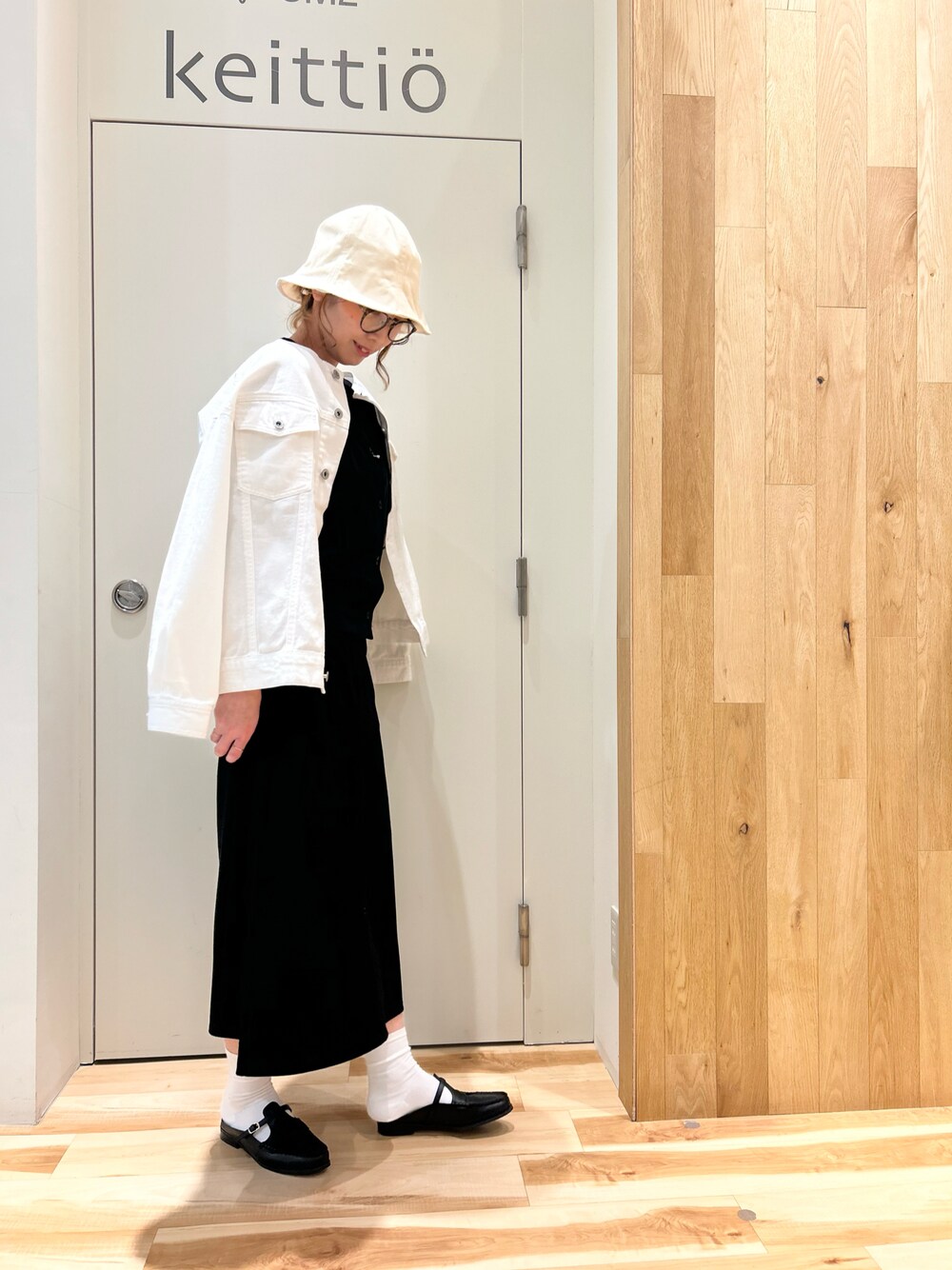 ホワイト系のノーカラージャケット、ブラック系のカーディガン/ボレロ、ブラック系のスカートを着用したレディースの春コーディネートの1枚目の写真