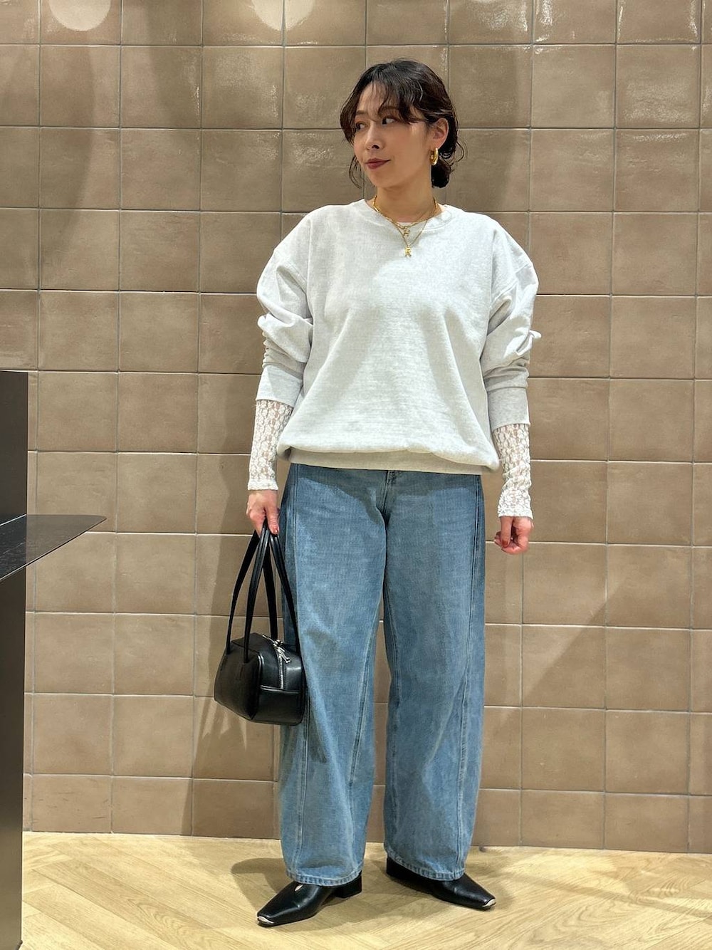 ブルー系のデニムパンツ、ブラック系のハンドバッグ、ブラック系のパンプスを着用したレディースの冬コーディネートの1枚目の写真