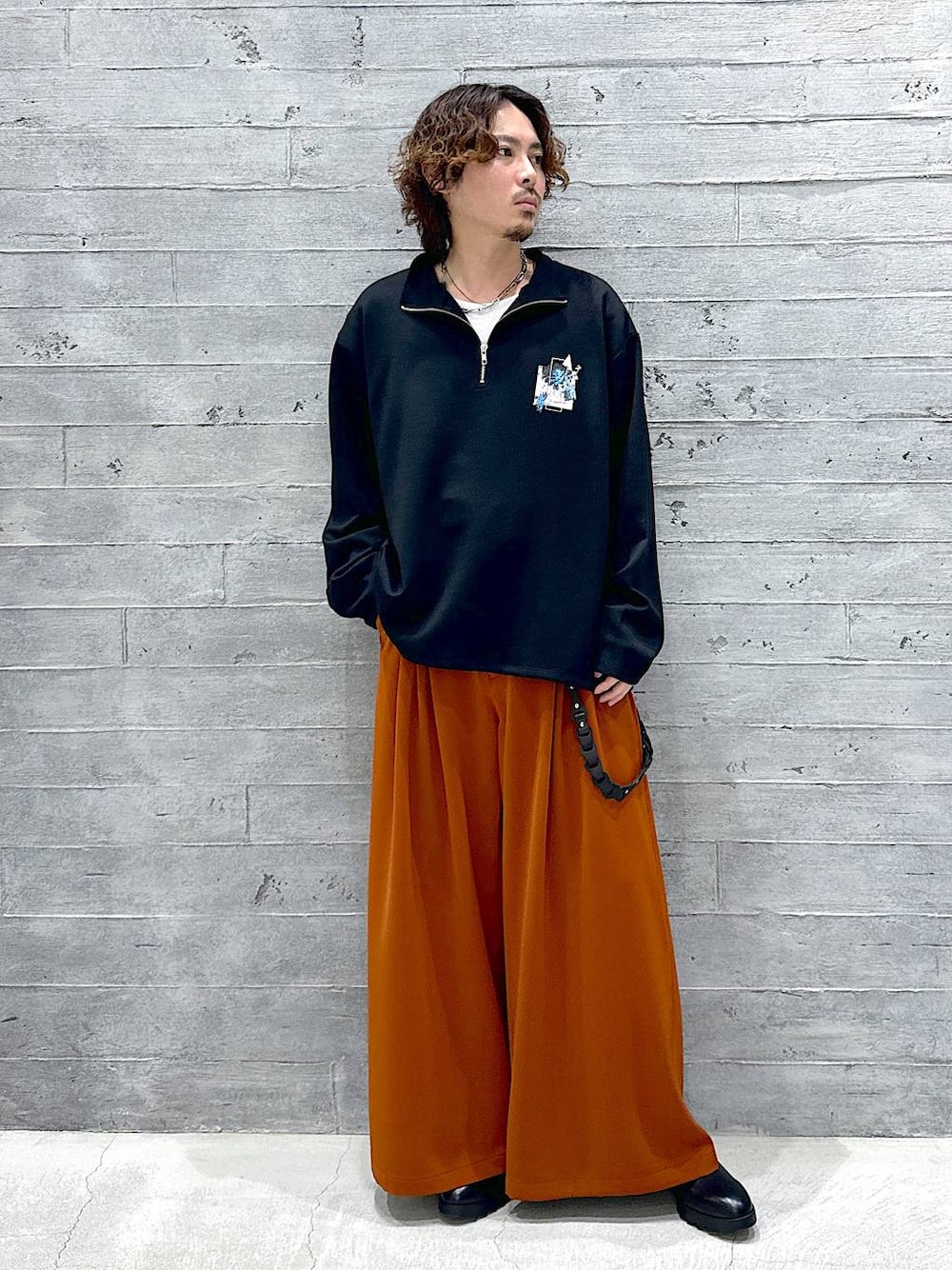 オレンジ系のスラックス、ブラック系のドレスシューズ、ブラック系のTシャツ/カットソーを着用したメンズの春コーディネートの1枚目の写真