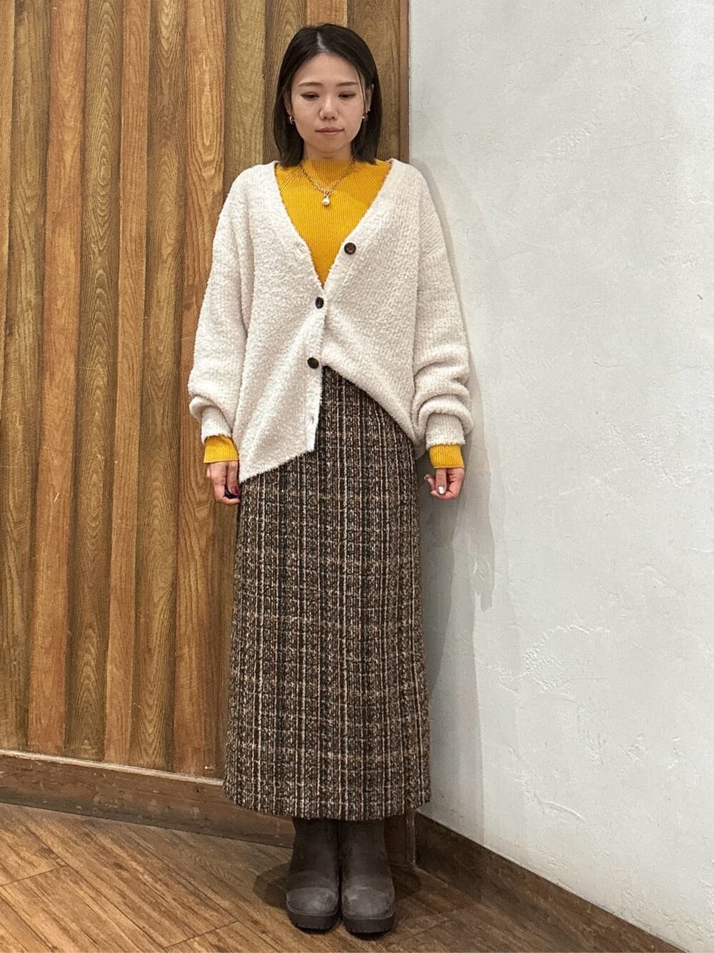 ベージュ系のカーディガン/ボレロ、ブラウン系のスカート、ブラウン系のブーツを着用したレディースの冬コーディネートの1枚目の写真