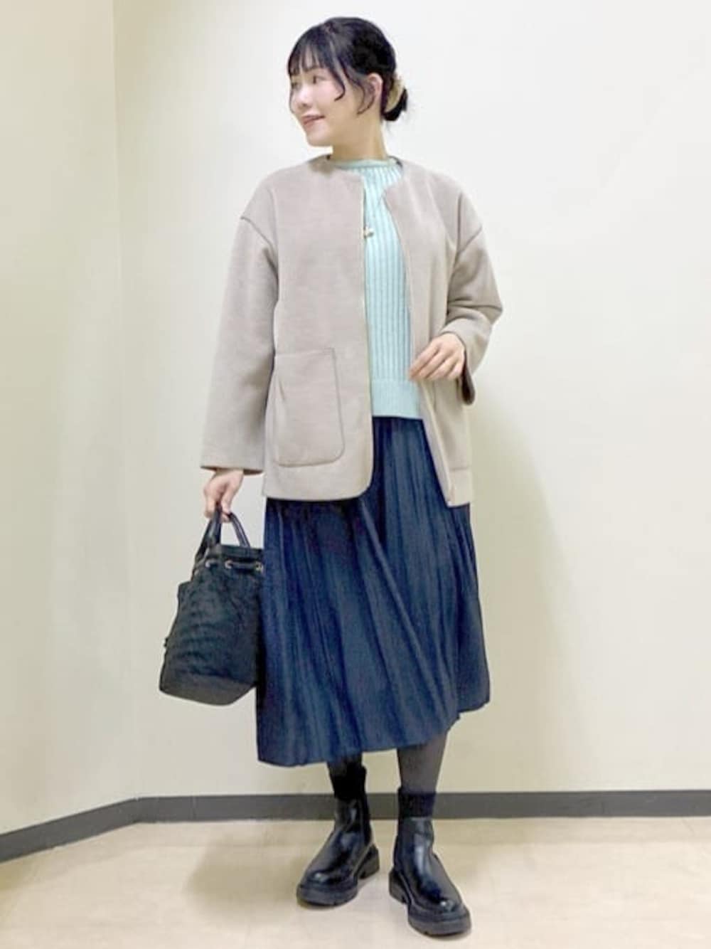 ベージュ系のノーカラーコート、グリーン系のニット/セーター、ブルー系のその他パンツを着用したレディースの冬コーディネートの1枚目の写真
