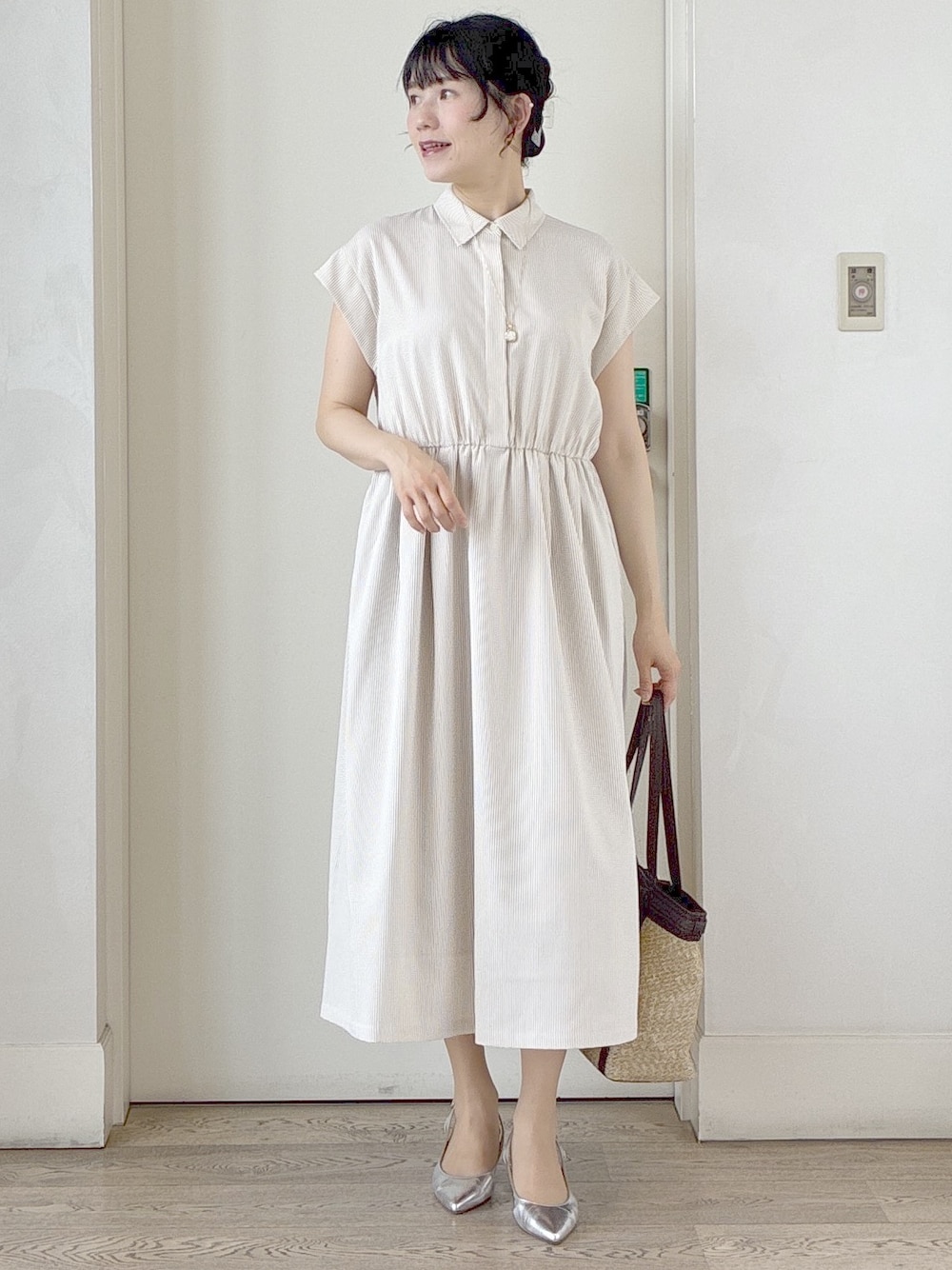ベージュ系のワンピース、イエロー系のトートバッグ、ホワイト系のネックレスを着用したレディースの夏コーディネートの1枚目の写真