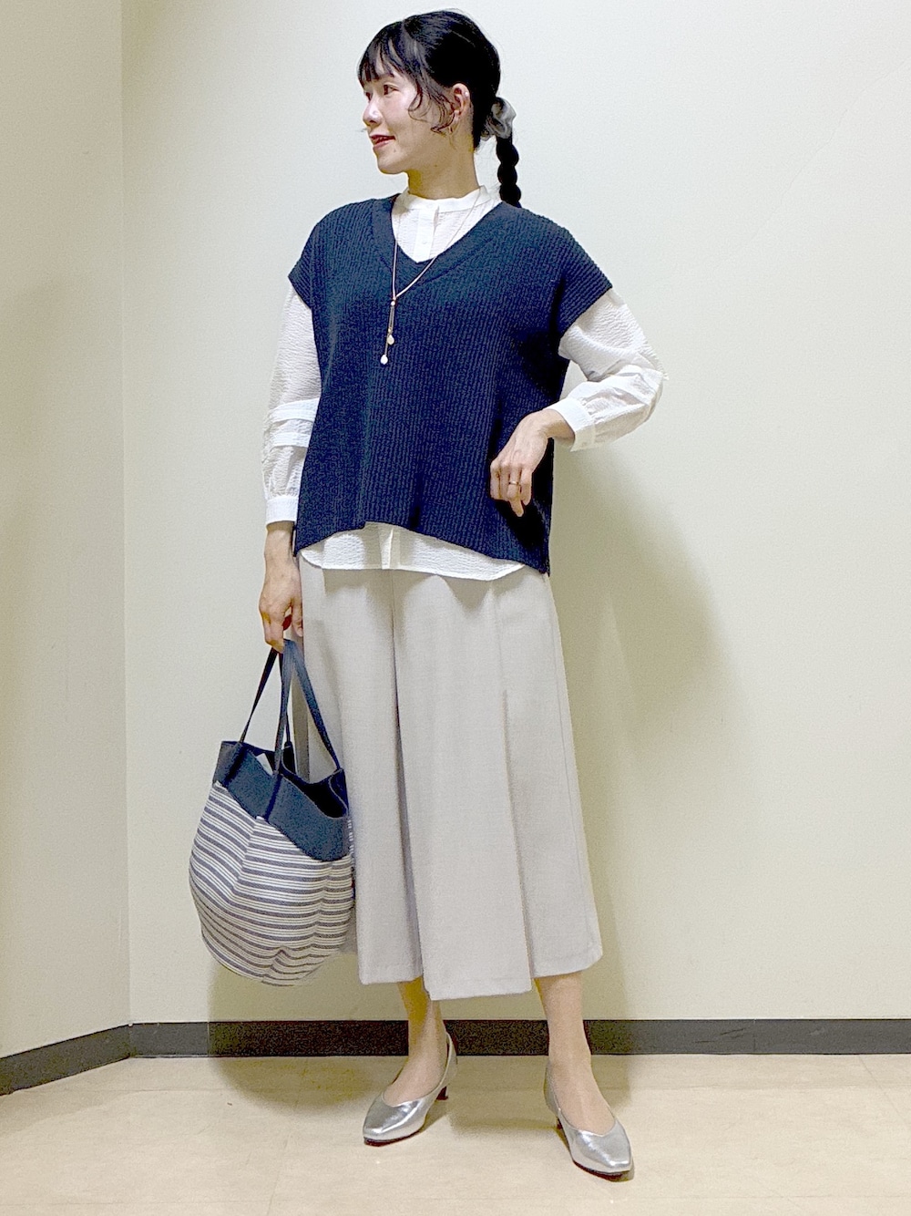 ブルー系のニット/セーター、ホワイト系のシャツ/ブラウス、ベージュ系のその他パンツを着用したレディースの春コーディネートの1枚目の写真