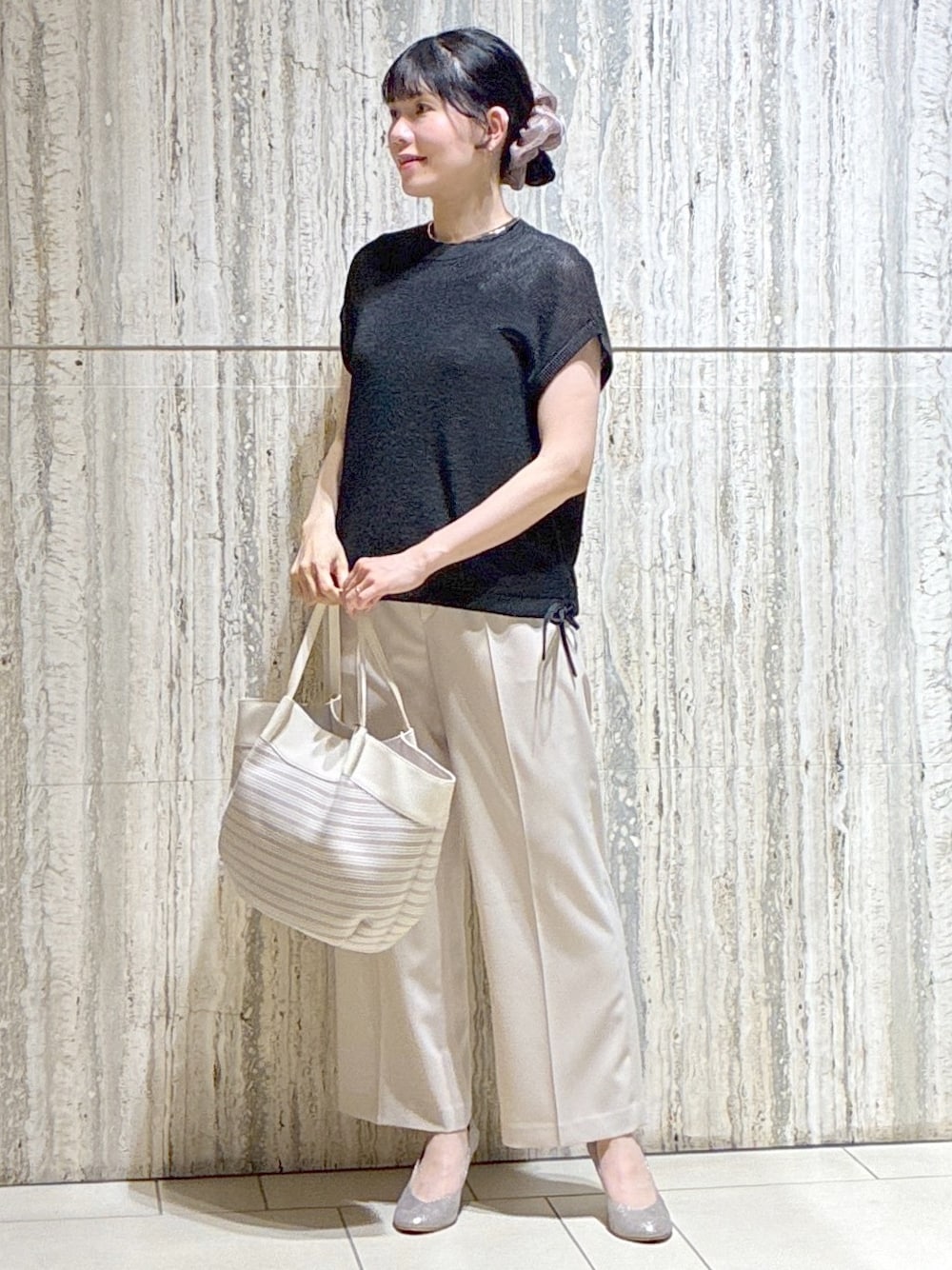 ブラック系のニット/セーター、ベージュ系のその他パンツ、ベージュ系のトートバッグを着用したレディースの夏コーディネートの1枚目の写真