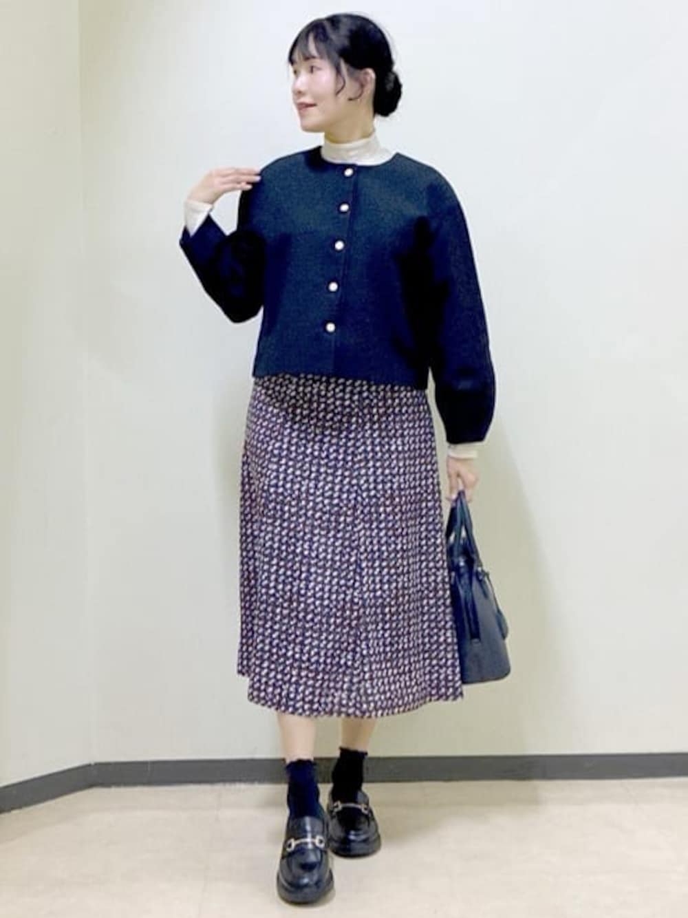ブルー系のノーカラージャケット、ベージュ系のニット/セーター、ブルー系のスカートを着用したレディースの冬コーディネートの1枚目の写真