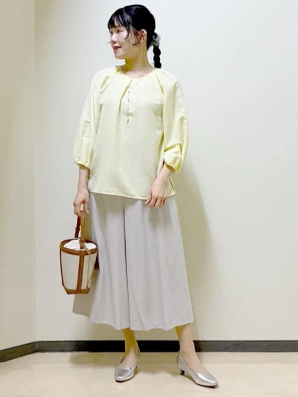 イエロー系のシャツ/ブラウス、シルバー系のパンプス、イエロー系のショルダーバッグを着用したレディースの春コーディネートの1枚目の写真