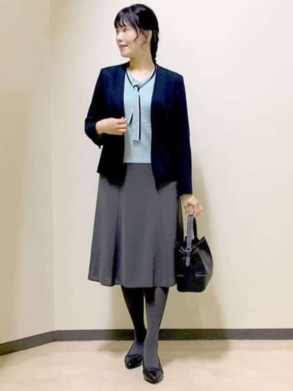 ブルー系のノーカラージャケット、ブルー系のニット/セーター、グレー系のスカートを着用したレディースの秋コーディネートの1枚目の写真