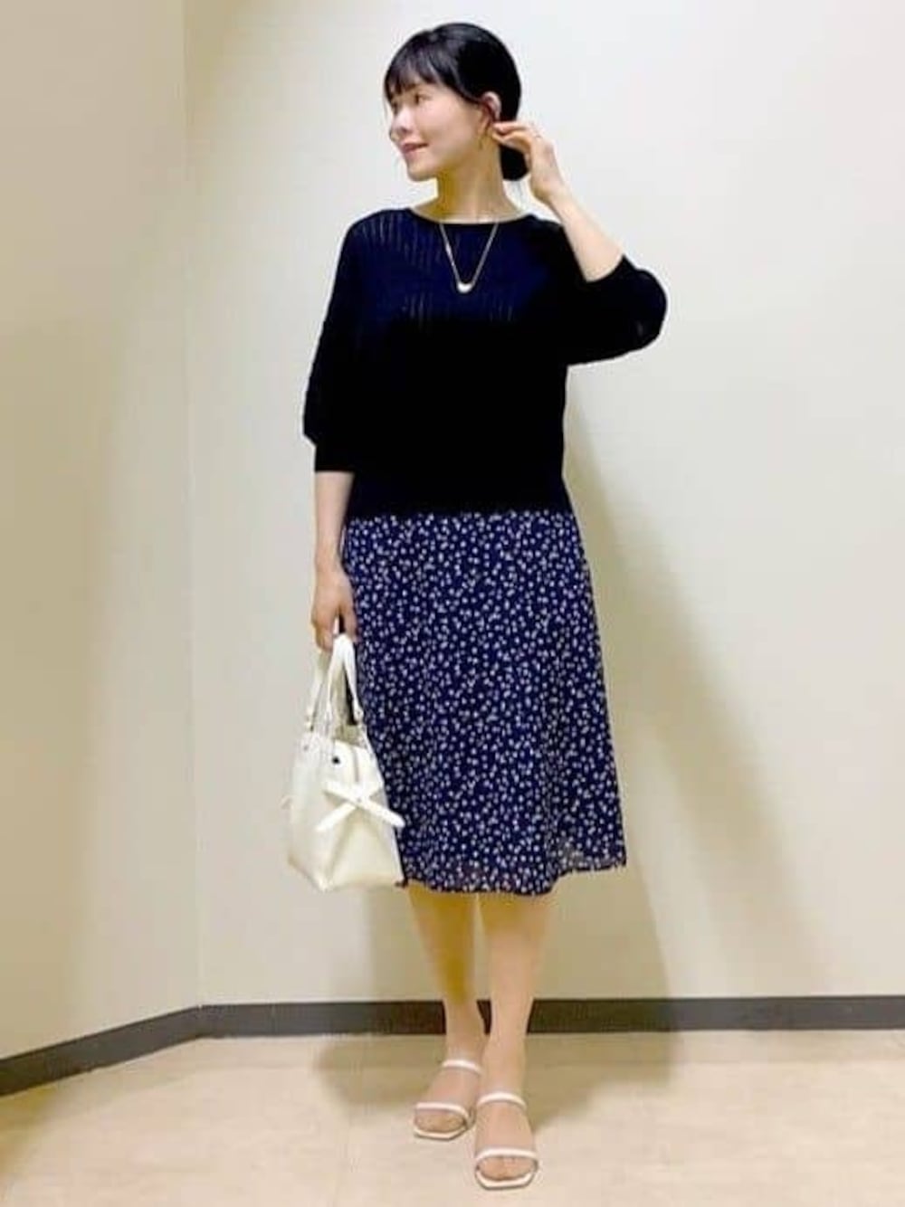 ブラック系のニット/セーター、ブルー系のスカート、ベージュ系のスカートを着用したレディースの夏コーディネートの1枚目の写真