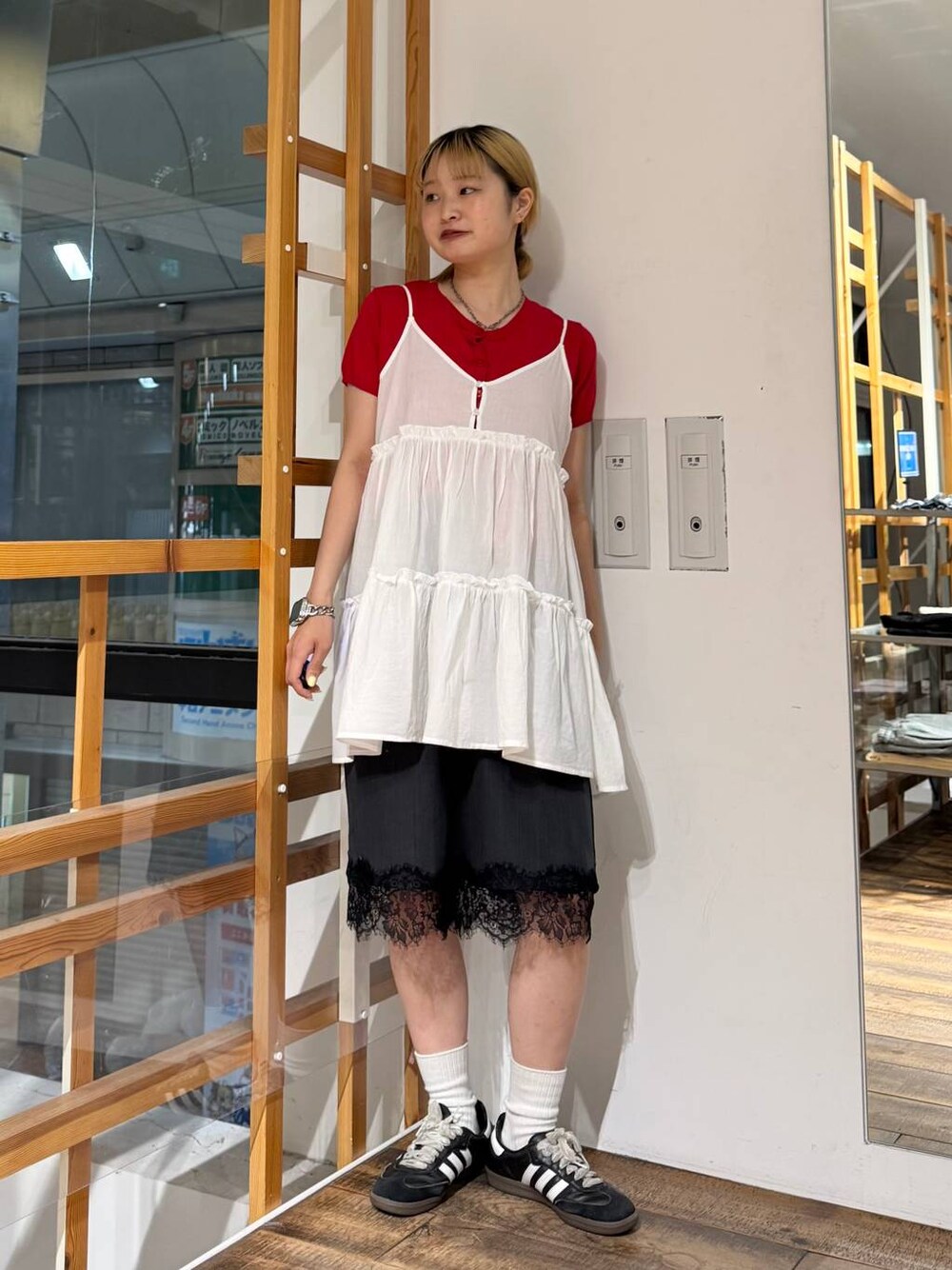 ホワイト系のチュニック、ブラック系のスラックス、レッド系のカーディガン/ボレロを着用したレディースの夏コーディネートの1枚目の写真