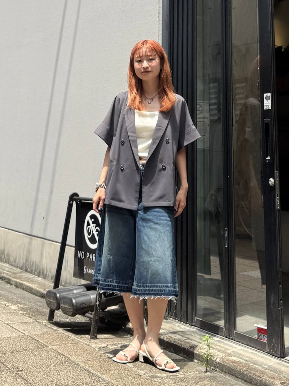 ブルー系のデニムパンツ、グレー系のテーラードジャケット、ホワイト系のキャミソールを着用したレディースの夏コーディネートの1枚目の写真