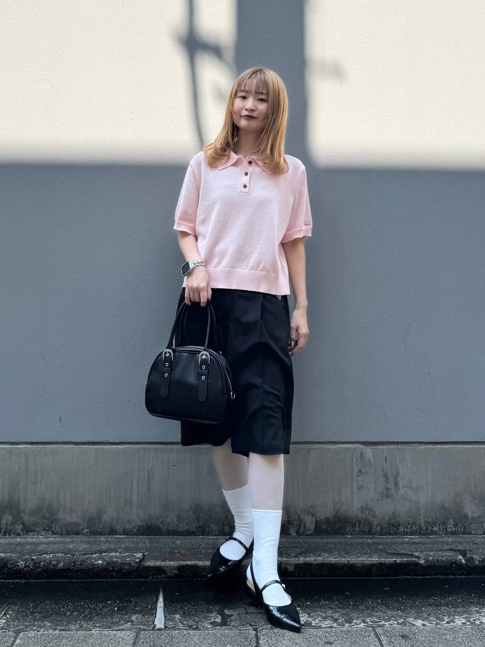 ブラック系のパンプス、ブラック系のスラックス、ブラック系のボストンバッグを着用したレディースの春コーディネートの1枚目の写真