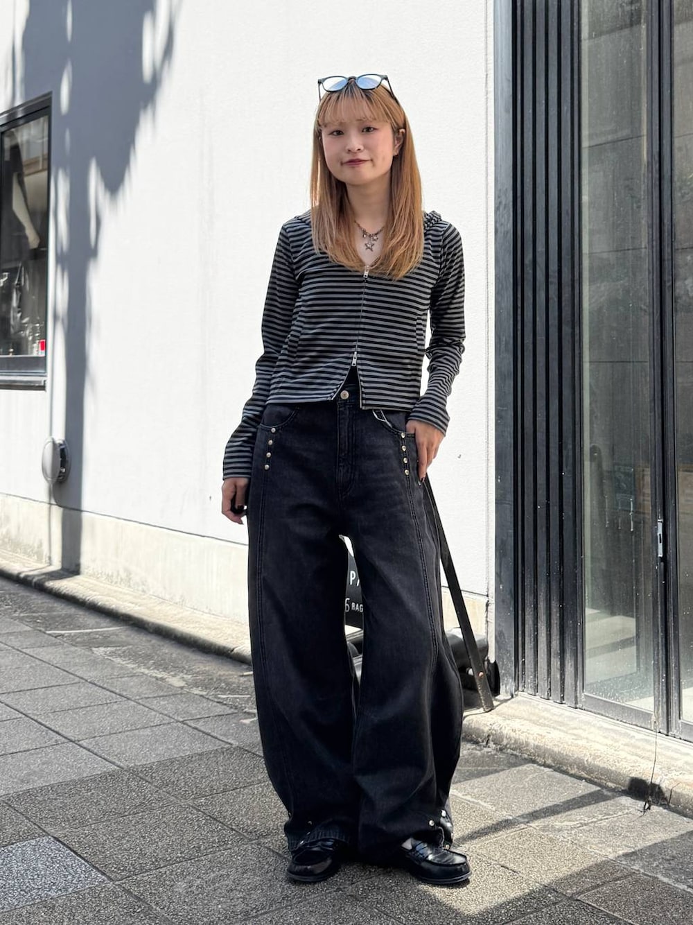 ブラック系のパーカー、グレー系のデニムパンツを着用したレディースの夏コーディネートの1枚目の写真