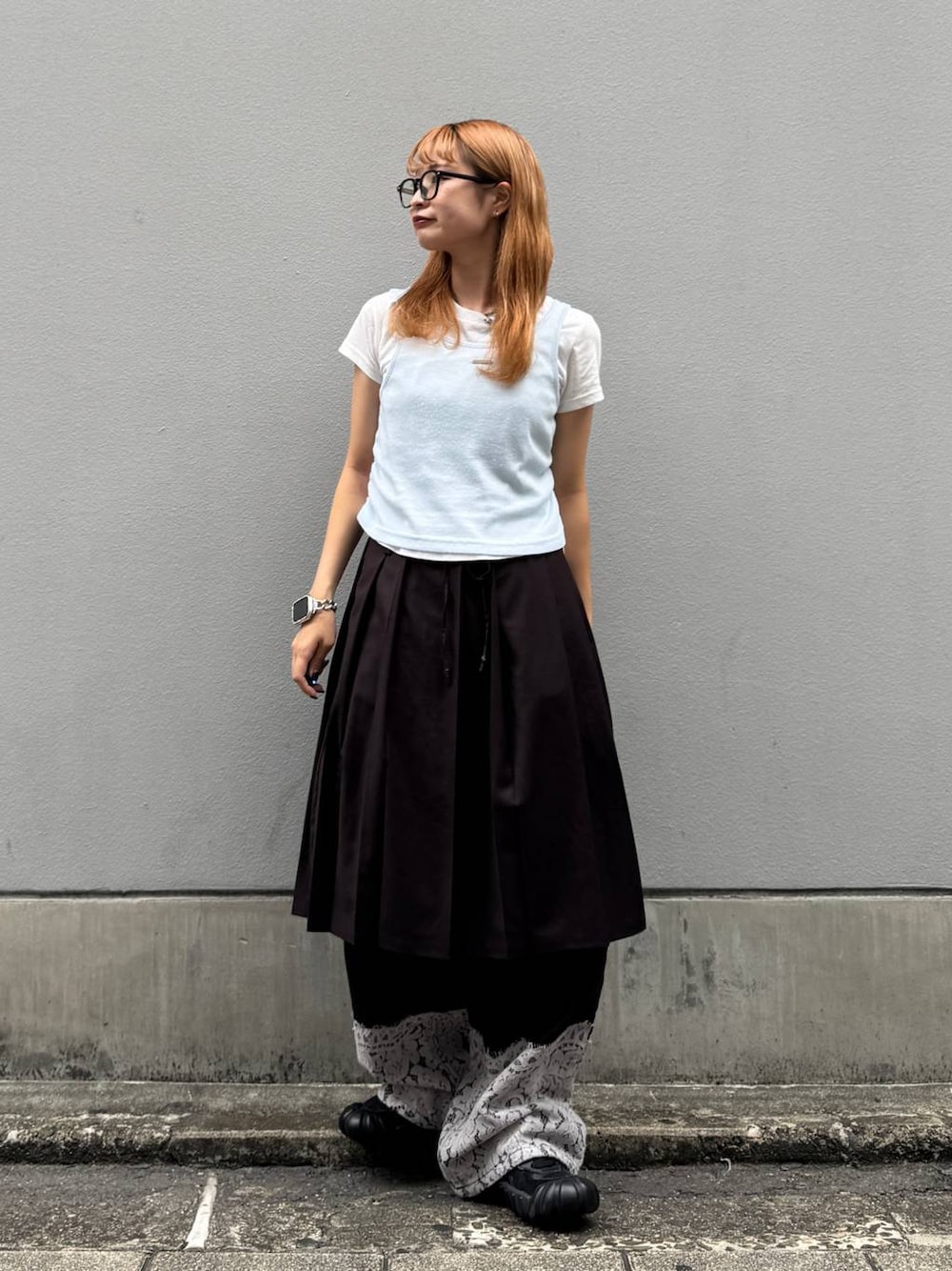 ブラウン系のスカート、ブラック系のデニムパンツ、ホワイト系のTシャツ/カットソーを着用したレディースの秋コーディネートの1枚目の写真