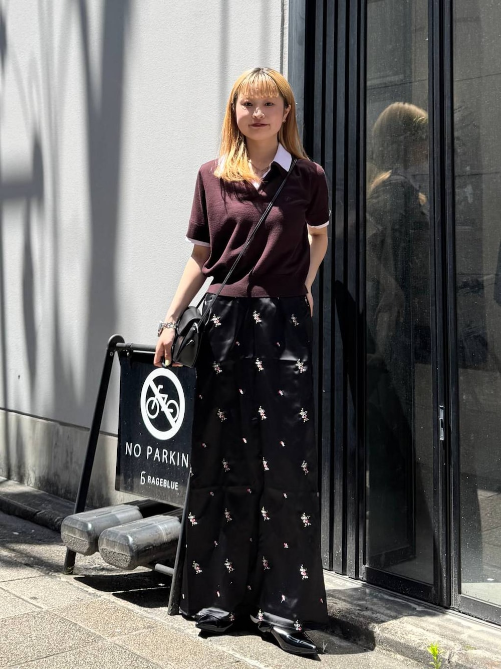 ブラック系のパンプス、ブラック系のスカート、ブラック系のショルダーバッグを着用したレディースの夏コーディネートの1枚目の写真
