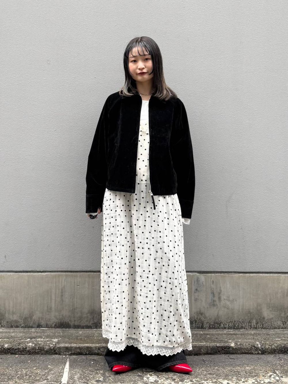 レッド系のパンプス、ブラック系のデニムパンツ、ブラック系のブルゾンを着用したレディースの春コーディネートの1枚目の写真