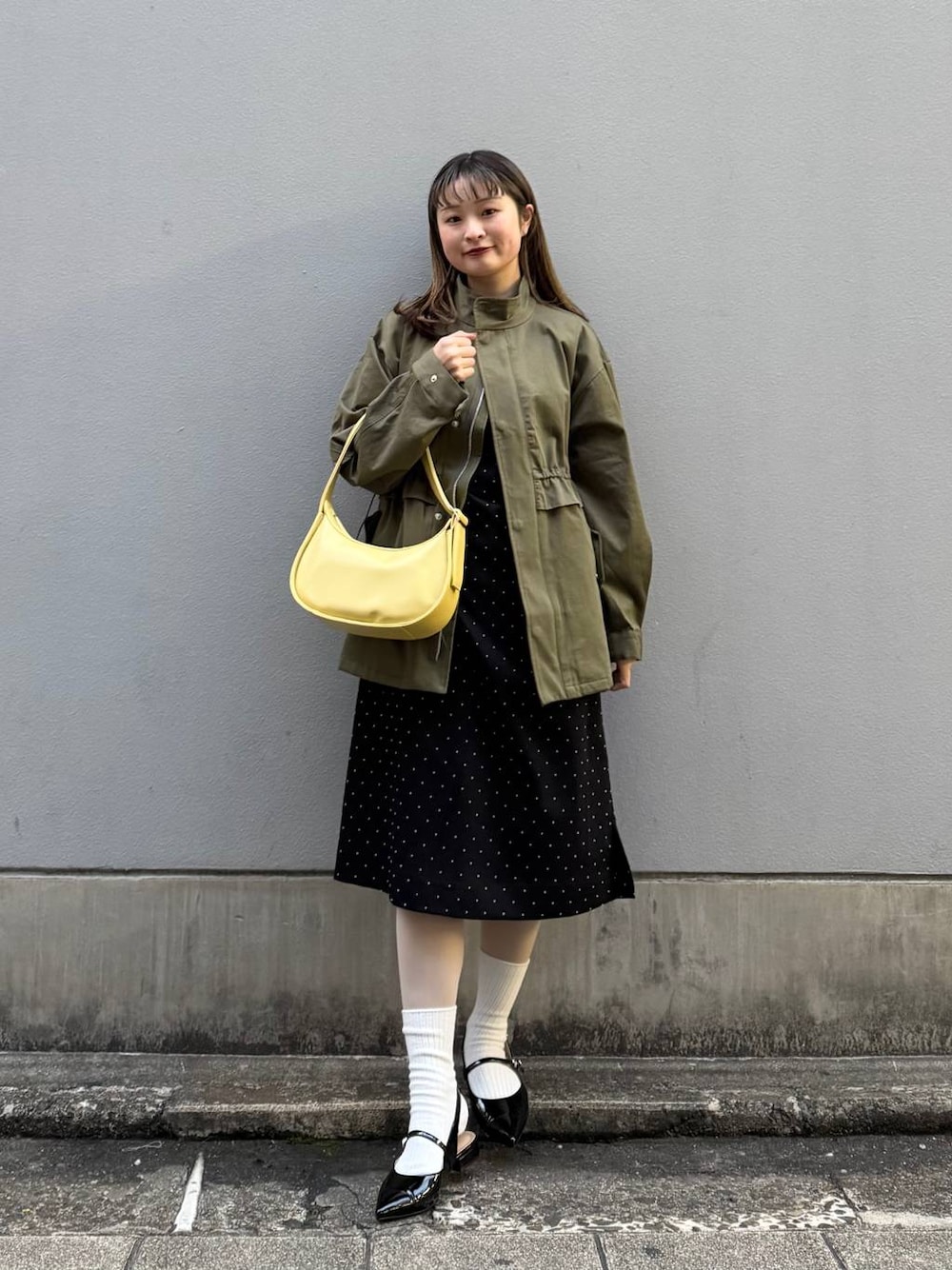 ブラック系のパンプス、イエロー系のショルダーバッグ、ブラック系のワンピースを着用したレディースの春コーディネートの1枚目の写真