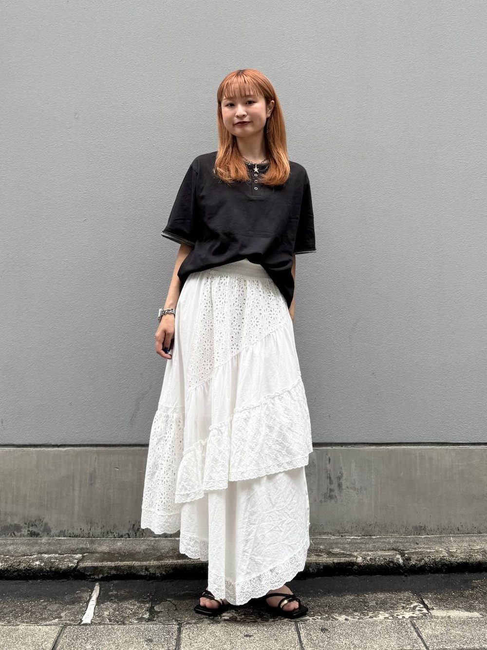ホワイト系のスカート、ブラック系のTシャツ/カットソー、ブラック系のサンダルを着用したレディースの夏コーディネートの1枚目の写真
