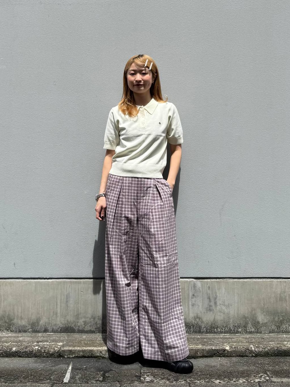 ピンク系のスラックス、ホワイト系のポロシャツを着用したレディースの夏コーディネートの1枚目の写真