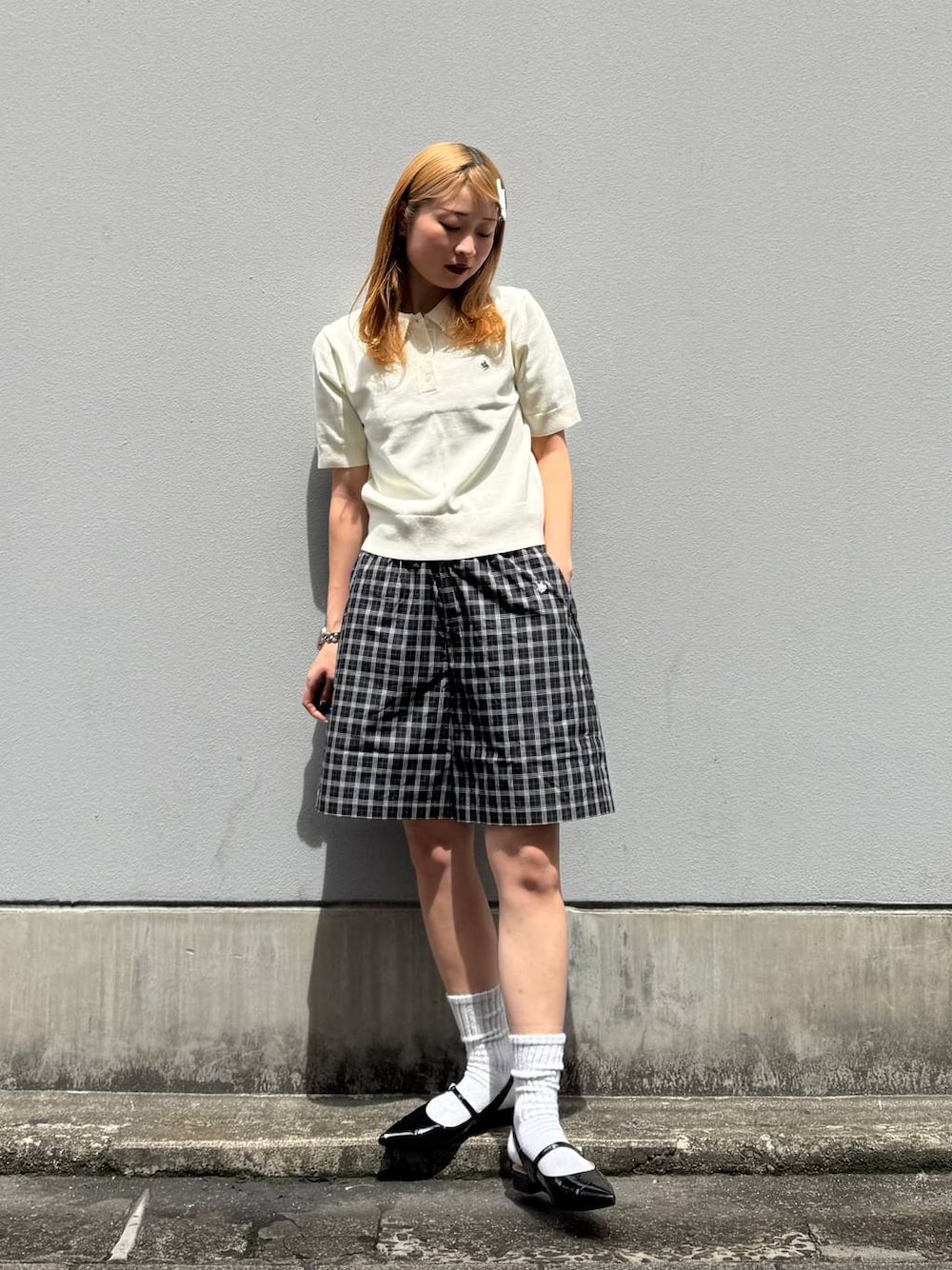 ブラック系のパンプス、ブラック系のその他パンツ、ホワイト系のポロシャツを着用したレディースの春コーディネートの1枚目の写真