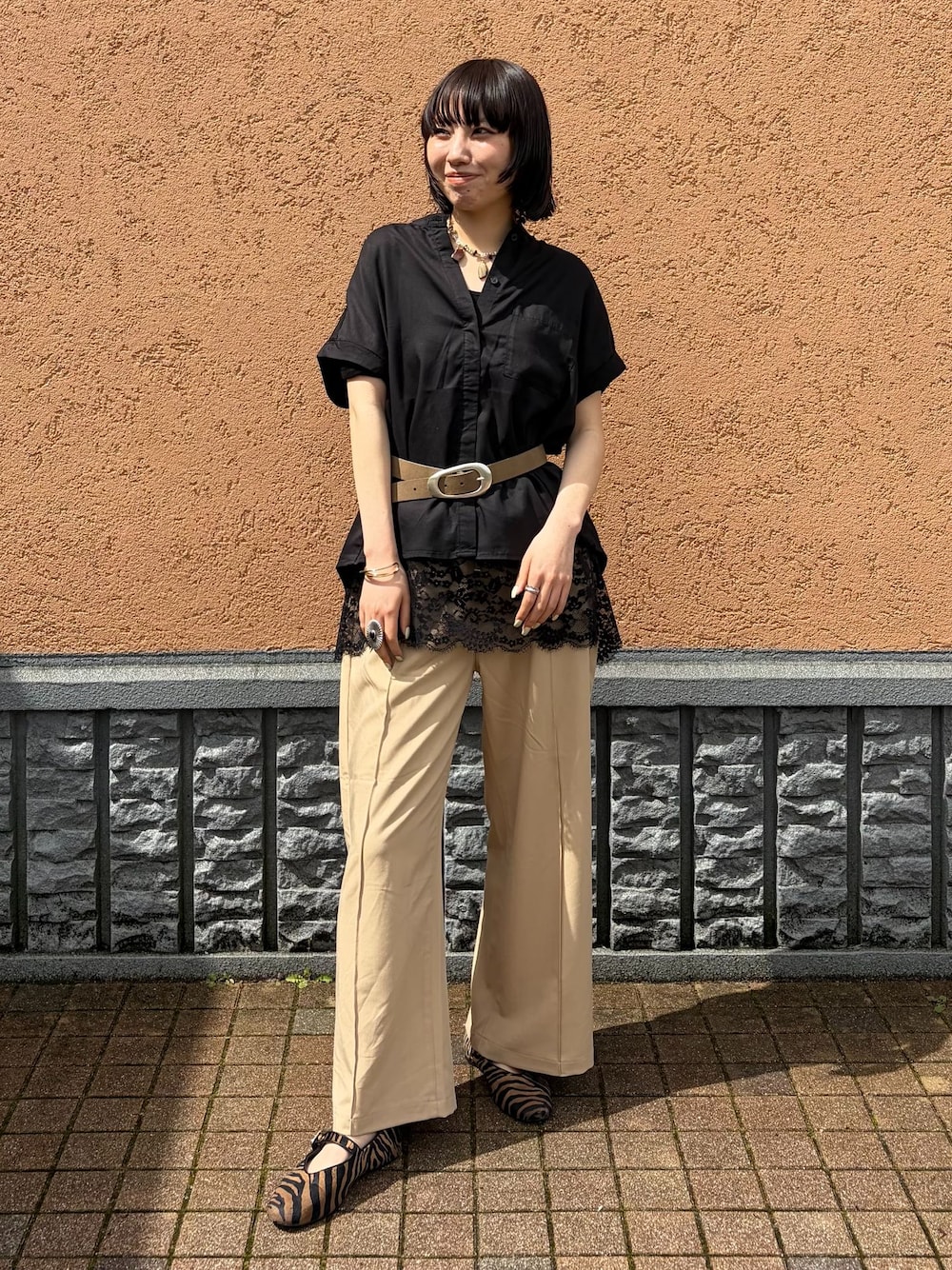 ベージュ系のスラックス、ブラック系のシャツ/ブラウス、ブラック系のキャミソールを着用したレディースの春コーディネートの1枚目の写真
