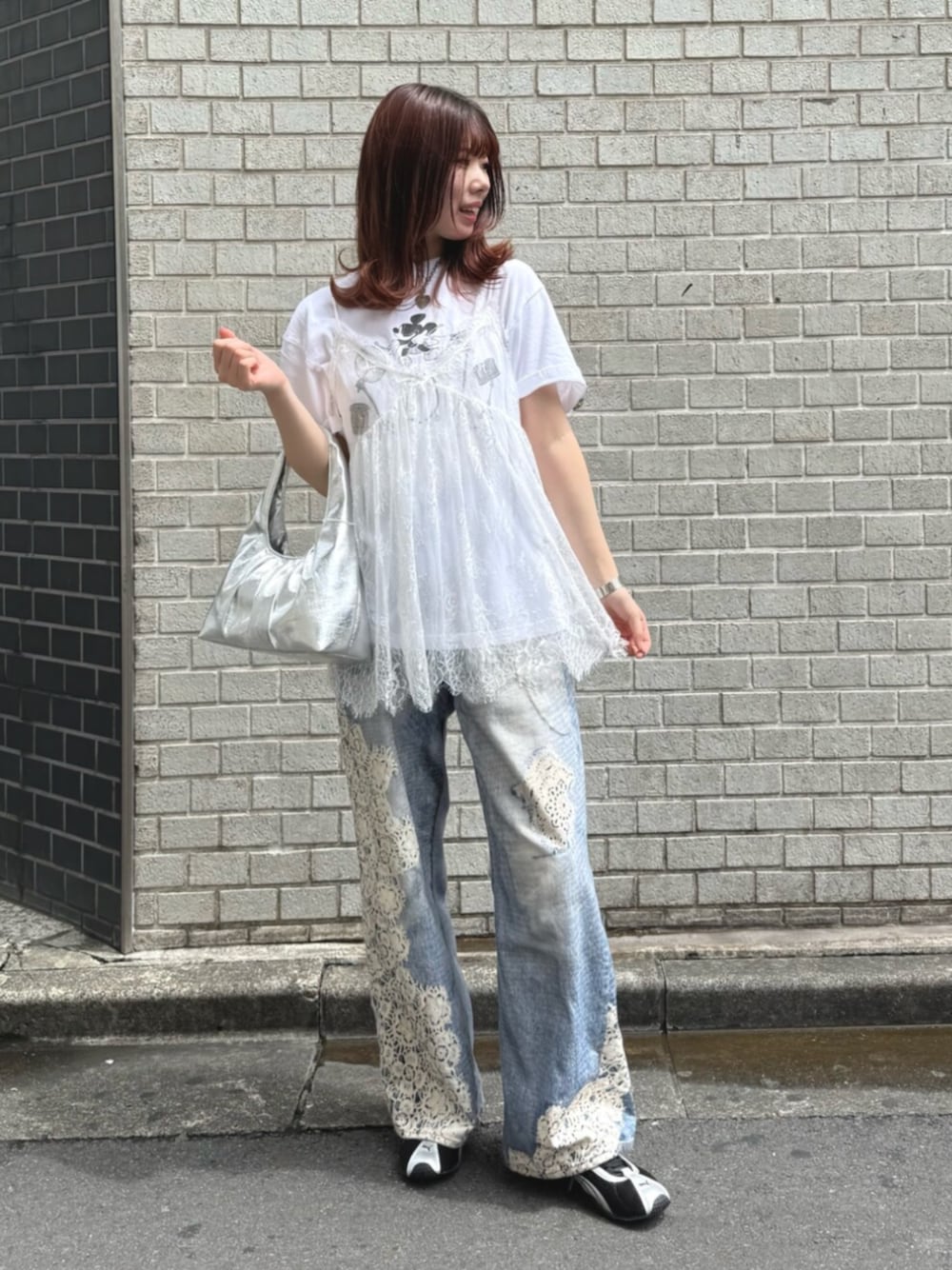 シルバー系のハンドバッグ、ブルー系のデニムパンツ、ホワイト系のキャミソールを着用したレディースの夏コーディネートの1枚目の写真