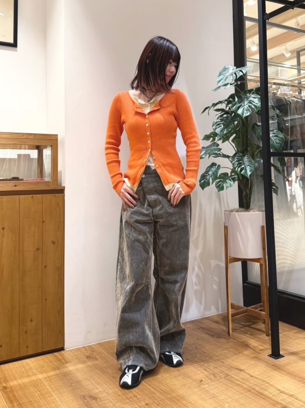 ベージュ系のデニムパンツ、オレンジ系のカーディガン/ボレロを着用したレディースの秋コーディネートの1枚目の写真