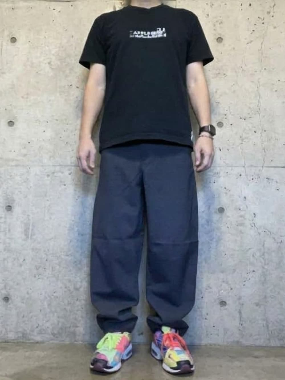 グレー系のその他パンツ、その他のスニーカー、ブラック系のTシャツ/カットソーを着用したメンズの秋コーディネートの1枚目の写真