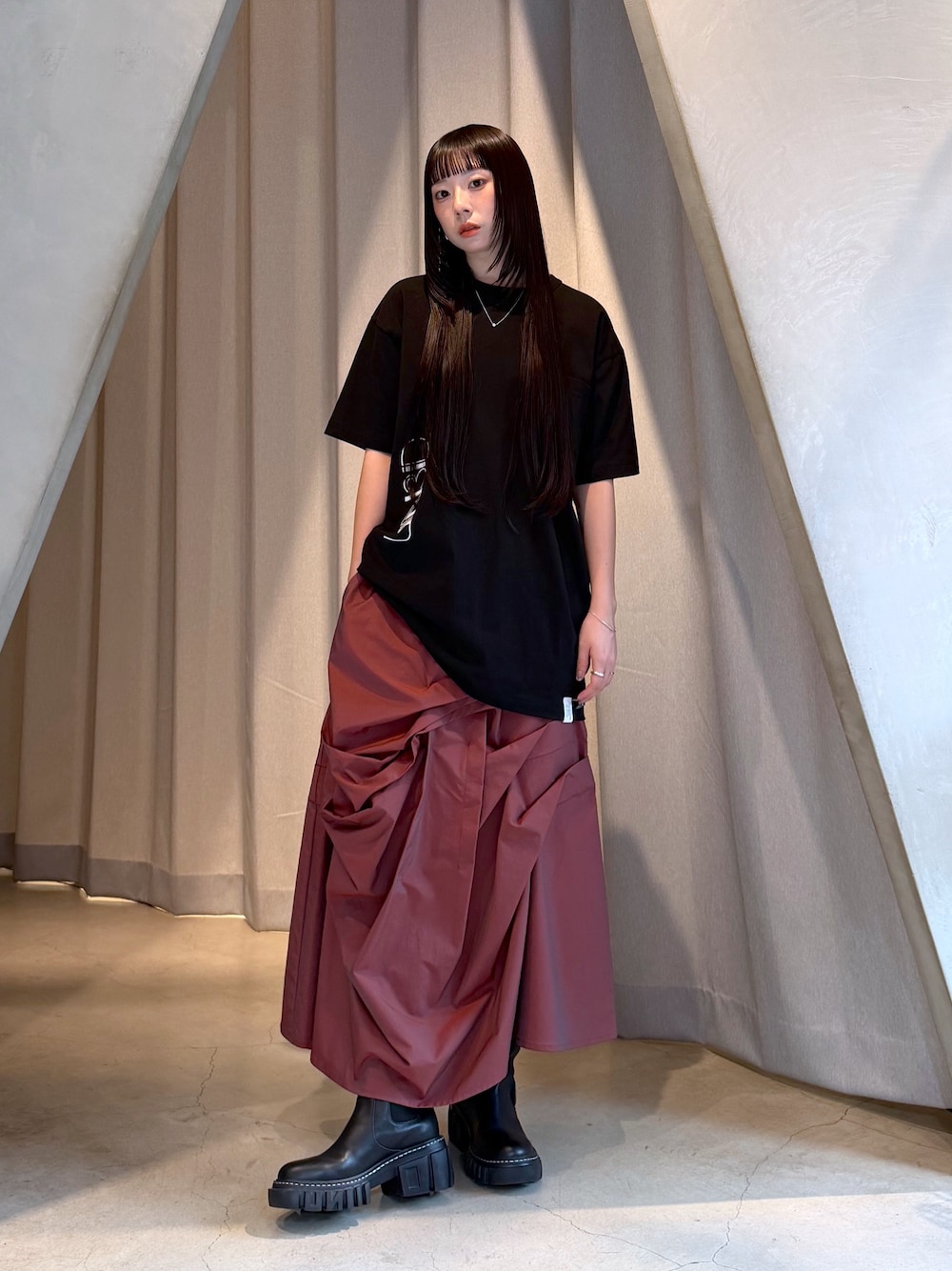 ブラック系のTシャツ/カットソー、レッド系のスカート、ブラック系のブーツを着用したレディースの秋コーディネートの1枚目の写真