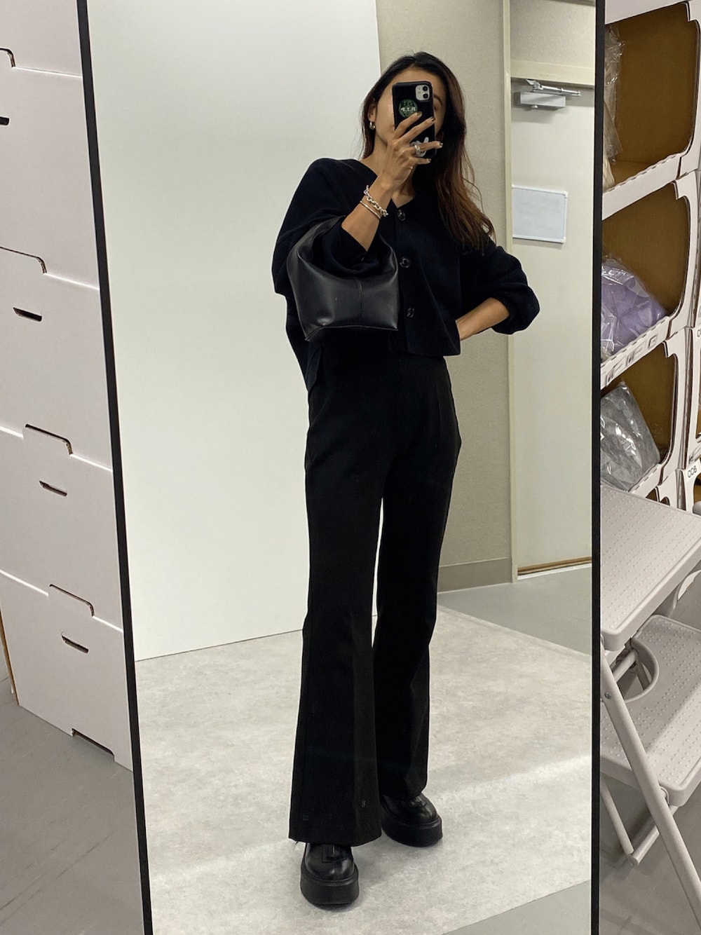 ブラック系のカーディガン/ボレロ、ブラック系のハンドバッグ、ブラック系のブーツを着用したレディースの秋コーディネートの1枚目の写真