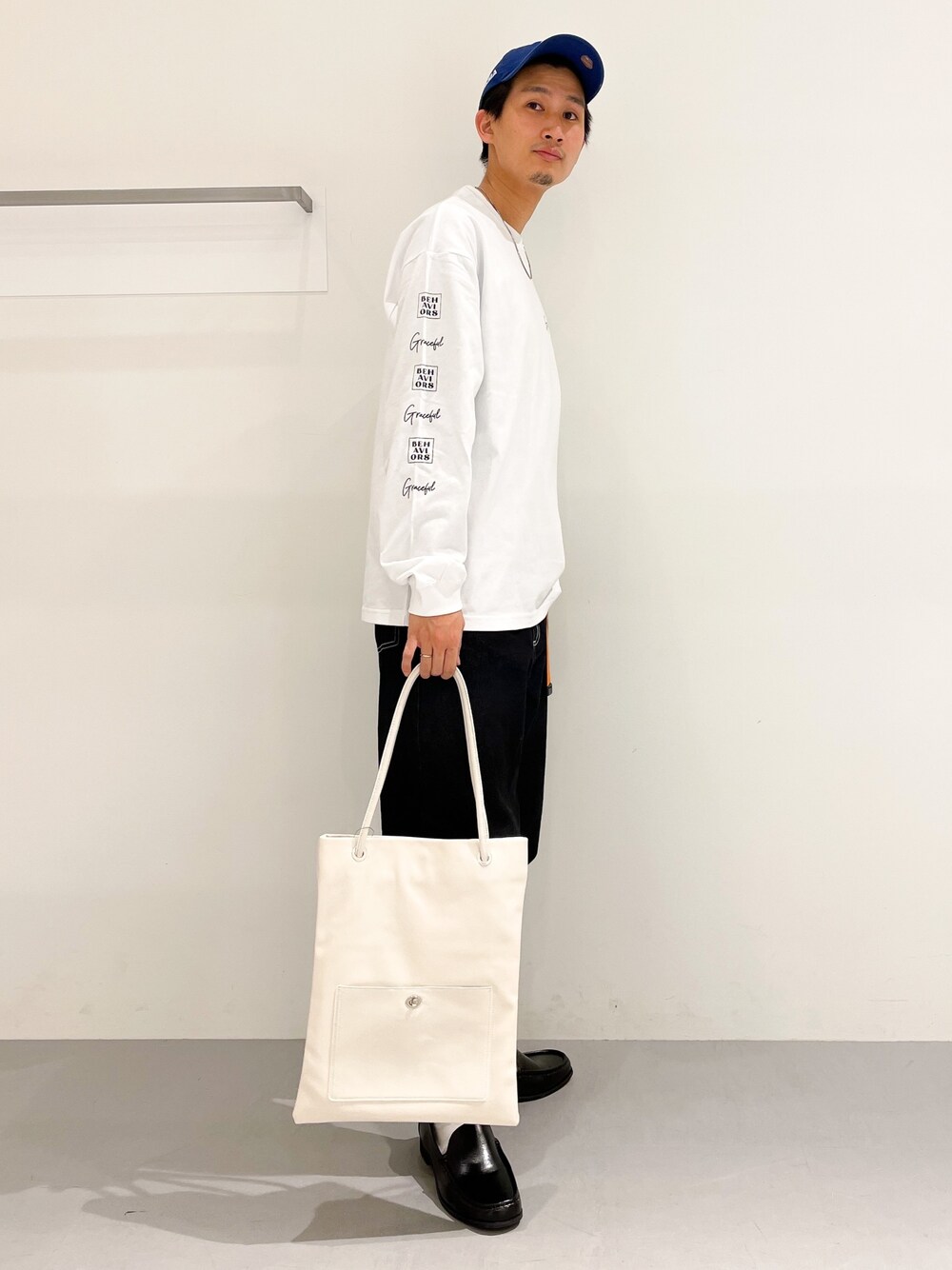 ホワイト系のTシャツ/カットソー、ブラック系のデニムパンツ、ホワイト系のトートバッグを着用したメンズの冬コーディネートの2枚目の写真